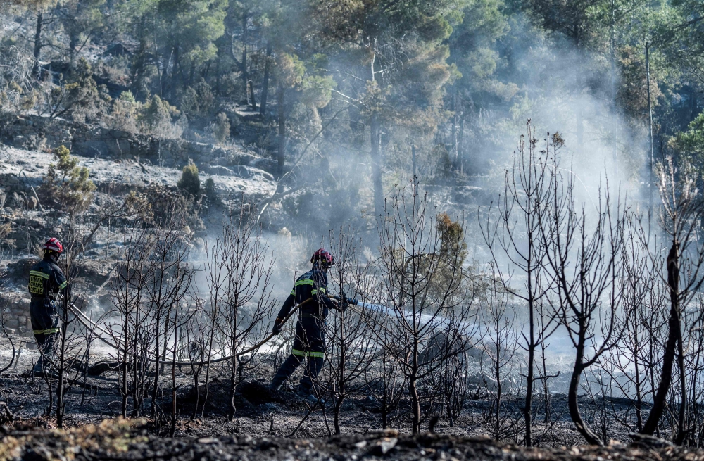 Fire fighters douse off a forest area burnt by a wildfire that began on March 23, in Fuente de la Reina, near Castellon, on March 29, 2023. Photo by Jose Jordan / AFP