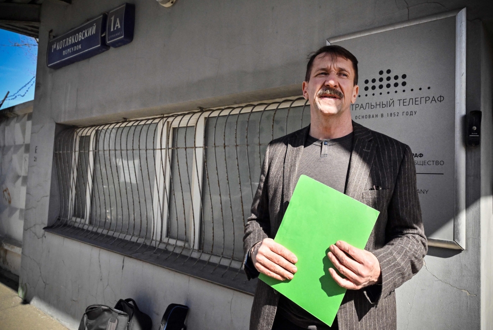 Liberal Democratic Party of Russia activist Viktor Bout, who was serving a 25-year sentence in a US prison and was exchanged in Abu Dhabi for American basketball star Brittney Griner in December, stands next to a telegraf office holding a telegram for former US president Donald Trump to share his prison experience during a symbolic action in Moscow on April 7, 2023.(Photo by Alexander Nemenov / AFP)