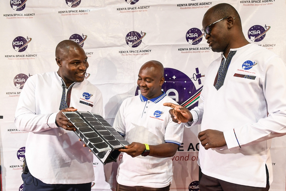 Kenya Space Agency (KSA) engineers Aloyce Were (L), Deche Bungule (C) and Andrew Nyawade who designed and developed the first Kenyan operational earth observation satellite Taifa-1, hold the prototype of Taifa-1 satellite before the fourth cancellation of its launch from the US's Vandenberg Air Force Base in California, at the University of Nairobi in Nairobi on April 14, 2023. (Photo by Simon MAINA / AFP)