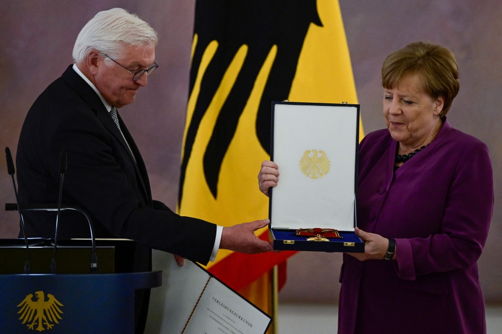German President Frank-Walter Steinmeier (left) awards the Order of Merit to former German Chancellor Angela Merkel at the Bellevue presidential palace in Berlin on April 17, 2023. (Photo by John MacDougall / AFP)
