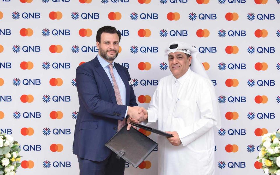 QNB and Mastercard officials exchange the agreement.
