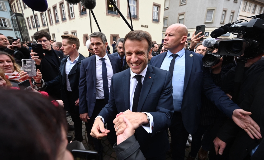 French President Emmanuel Macron shakes hands with people during a visit in Selestat, eastern France, on April 19, 2023. (Photo by Frederick Florin / AFP)