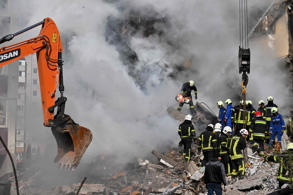 Rescuers search for survivors in the rubble next to a damaged residential building in Uman, around 215km south of Kyiv, on April 28, 2023, after Russian missile strikes targeted several Ukrainian cities overnight. (Photo by Sergei Supinsky / AFP)