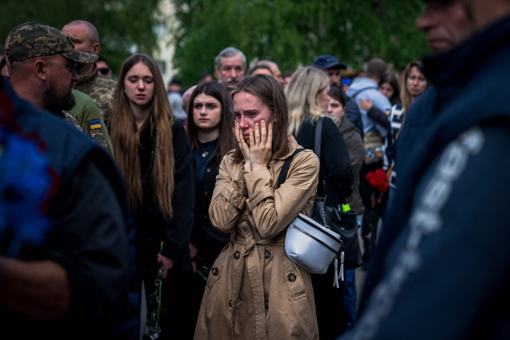 A woman reacts during the funeral ceremony of Ukrainian serviceman Valerii Sosnovskii who died near Bakhmut, Donetsk region in Poltava on May 11, 2023, amid the Russian invasion of Ukraine. (Photo by Ihor Tkachov / AFP)
