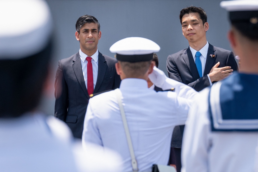 Britain's Prime Minister Rishi Sunak (L) and Japan's State Minister of Defence Toshiro Ino inspect the guard of honour on board the Japanese aircraft carrier JS Izumo during a visit to the Japan Maritime Self-Defence Force (JMSF) at the Yokosuka Naval Base in Yokosuka, ahead of the G7 Leaders' Summit, on May 18, 2023. (Photo by Stefan Rousseau / POOL / AFP)
