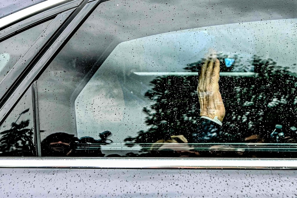 Former Italian premier Silvio Berlusconi waves from inside his car as he leaves on May 19, 2023 the San Raffaele hospital in Milan after being discharged. (Photo by Piero Cruciatti / AFP)