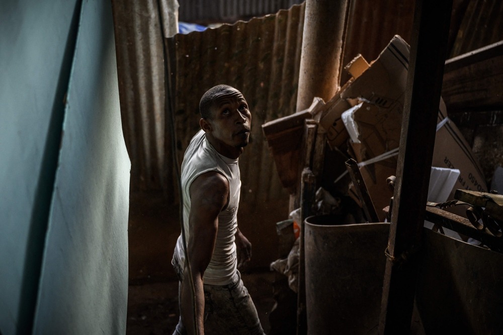 A man looks up as he dismantles his makeshift house in a shantytown of 