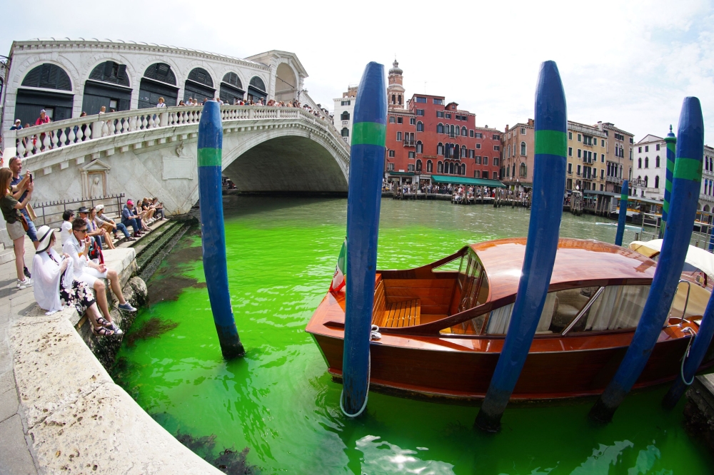 A photo taken and made available on May 28, 2023 by Italian news agency Ansa, shows fluorescent green waters below the Rialto Bridge in Venice's Grand Canal. (Photo by Stringer / Ansa / AFP) 