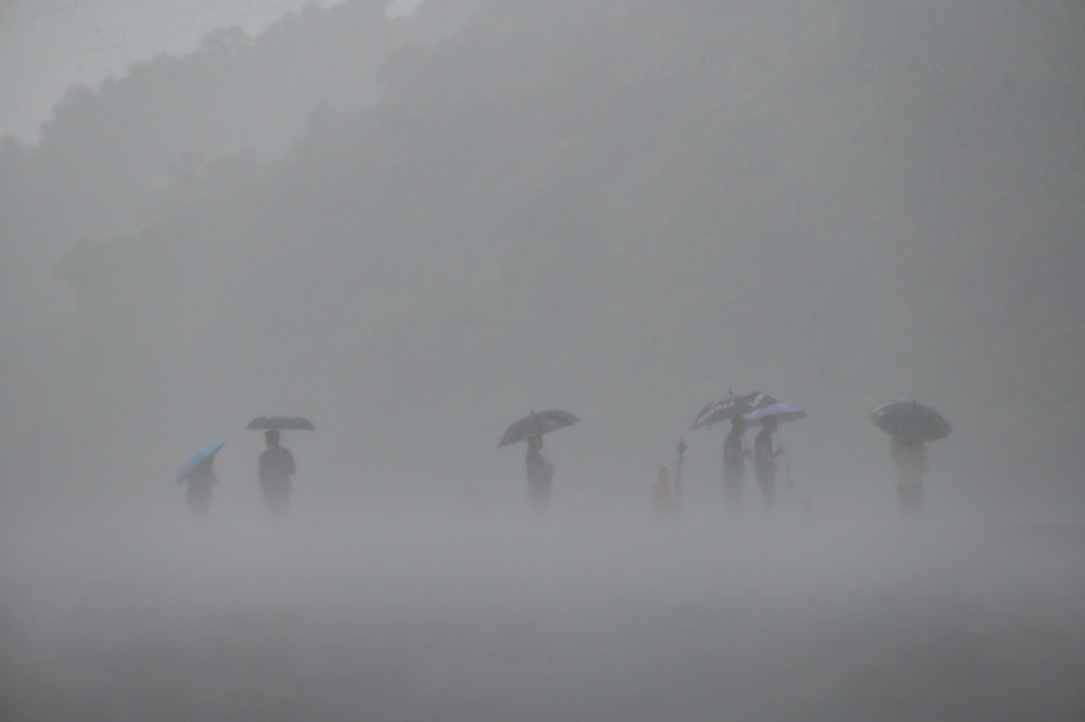 People use umbrellas to shield themselves from the rain in New Taipei City as typhoon Mawar approaches on the east coast of Taiwan on May 31, 2023. Photo by Sam Yeh / AFP