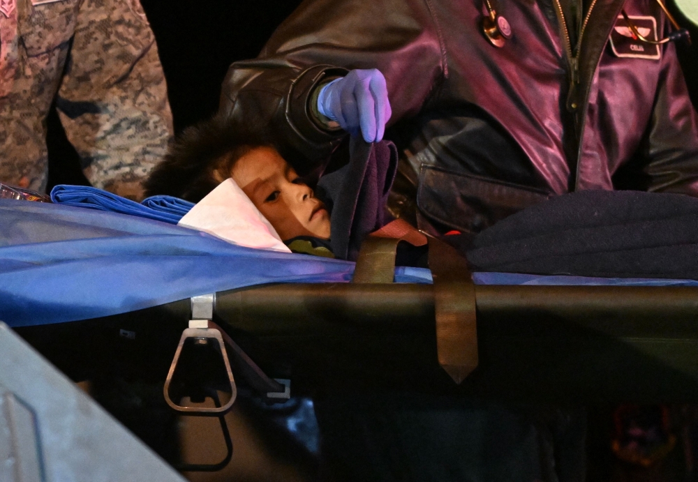 One of the four Indigenous children is stretchered out of a plane upon landing at the CATAM military base in Bogota on June 10, 2023. (Photo by Juan Barreto / AFP)