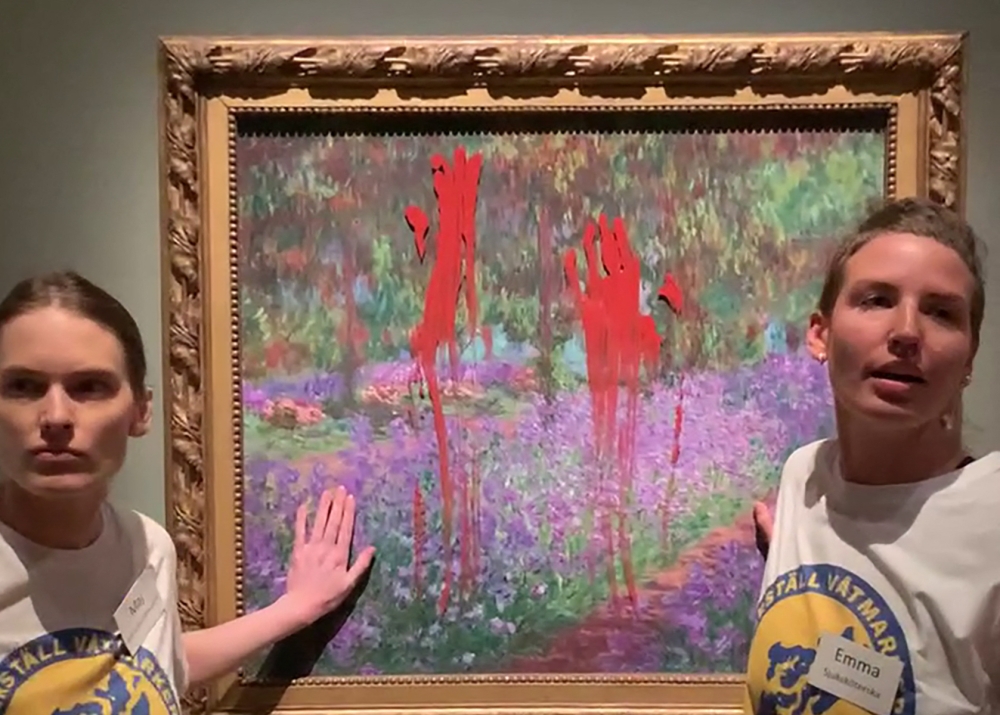 This handout video grab taken from footage provided by action network Aterstall Vatmarker on June 14, 2023 shows two activists standing next to the painting 