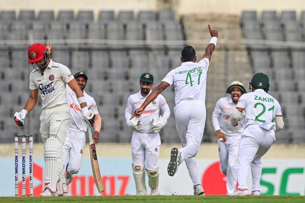 Bangladesh's Shoriful Islam (2R) celebrates with teammates after taking the wicket of Afghanistan's Ibrahim Zadran (L) during the third day of the Test cricket match between Bangladesh and Afghanistan at the Sher-e-Bangla National Cricket Stadium in Dhaka on June 16, 2023. (Photo by Munir uz ZAMAN / AFP)