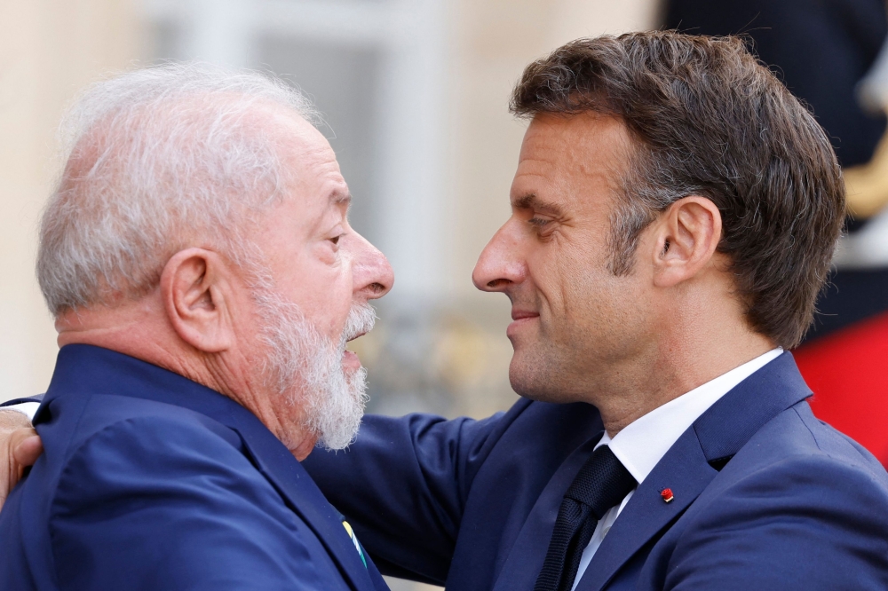 French President Emmanuel Macron (right) embraces Brazil's President Luiz Inacio Lula da Silva as he departs after their meeting at the Elysee Palace, amid the New Global Financial Pact Summit in Paris on June 23, 2023. (Photo by Ludovic Marin / AFP)