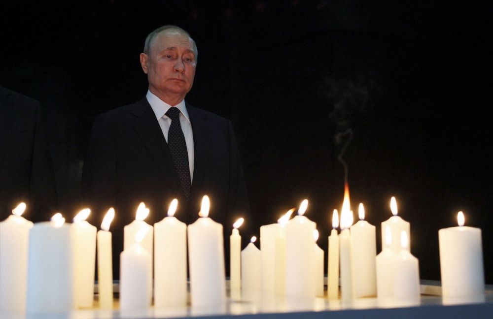 Russia's President Vladimir Putin stands in front of candles at the memorial 