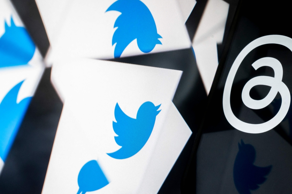 This photo illustration created in Washington, DC, on July 5, 2023, shows the Twitter logo reflected near the logo for Threads, an Instagram app. Facebook owner Meta's new Threads app, meant to compete with Twitter, was available for pre-order on mobile app stores on iPhone and Android operating systems on July 5, 2023. (Photo by Stefani Reynolds / AFP)
