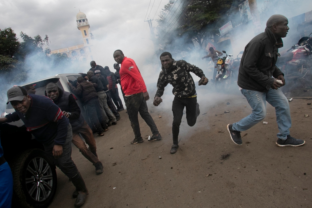 Protestors retreat from a cloud of teargas after police fired canisters at the convoy of opposition leaders led by Raila Odinga during demonstrations against the high cost of living in Nairobi on July 7, 2023. (Photo by Tony Karumba / AFP)