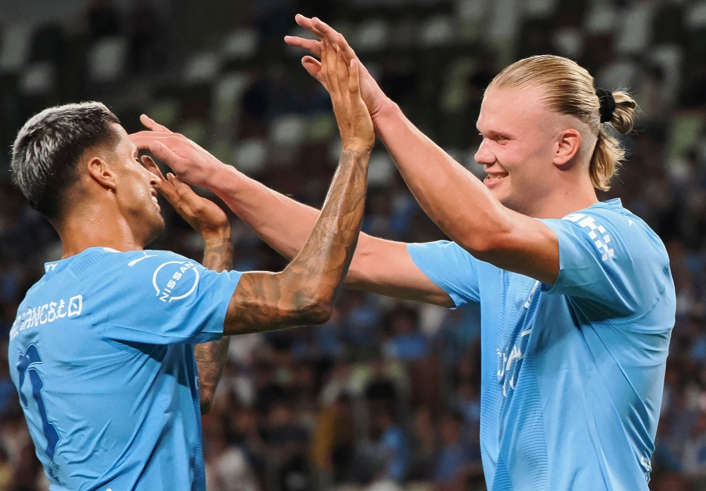 Manchester City forward Erling Haaland (R) is congratulated by defender Joao Cancelo for his goal during the J-League World Challenge 2023 football match between English Premier League champion Manchester City and Yokohama F-Marinos at the National Stadium in Tokyo on July 23, 2023. (Photo by Toshifumi KITAMURA / AFP)
