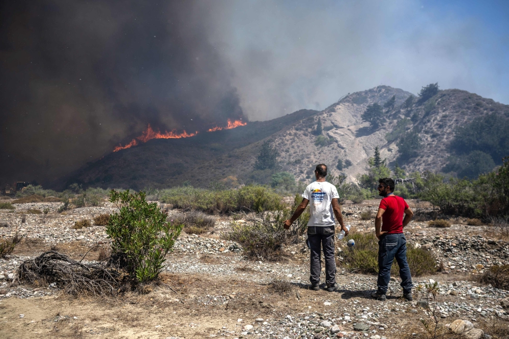 Locals watch the wildfires near the village of Vati, just north of the coastal town Gennadi, in the southern part of the Greek island of Rhodes on July 25, 2023. Photo by Angelos Tzortzinis / AFP