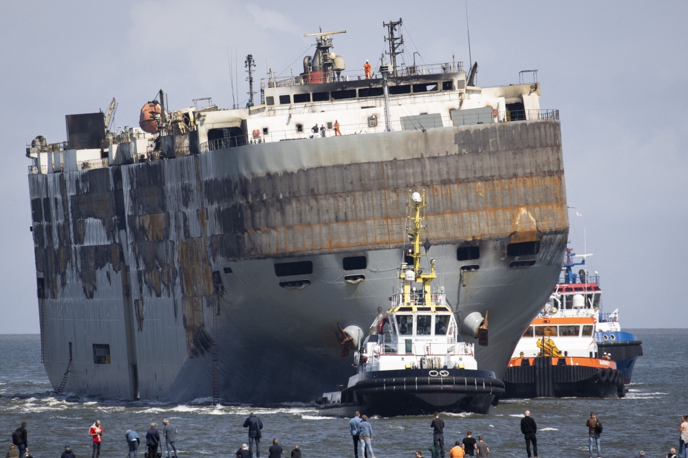 People look at the Panamanian-registered car carrier ship Fremantle Highway, from Eemshaven, on August 3, 2023 as it is being towed to a new location after a fire broke out late on July 25, 2023, killing one crew member, and prompting a massive effort to extinguish the flames. Photo by Vincent Jannink / ANP / AFP