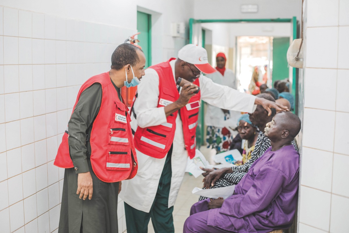 A QRCS volunteer checking the eyes of a patient.