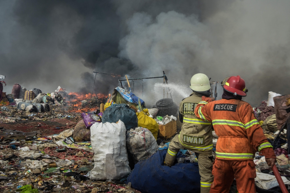 Firefighters try to extinguish a fire that has been burning for five days, causing air pollution for some 12,000 residents in the surrounding area, at the landfill in Sarimukti on the outskirts of Bandung, West Java on August 24, 2023. Photo by Timur MATAHARI / AFP