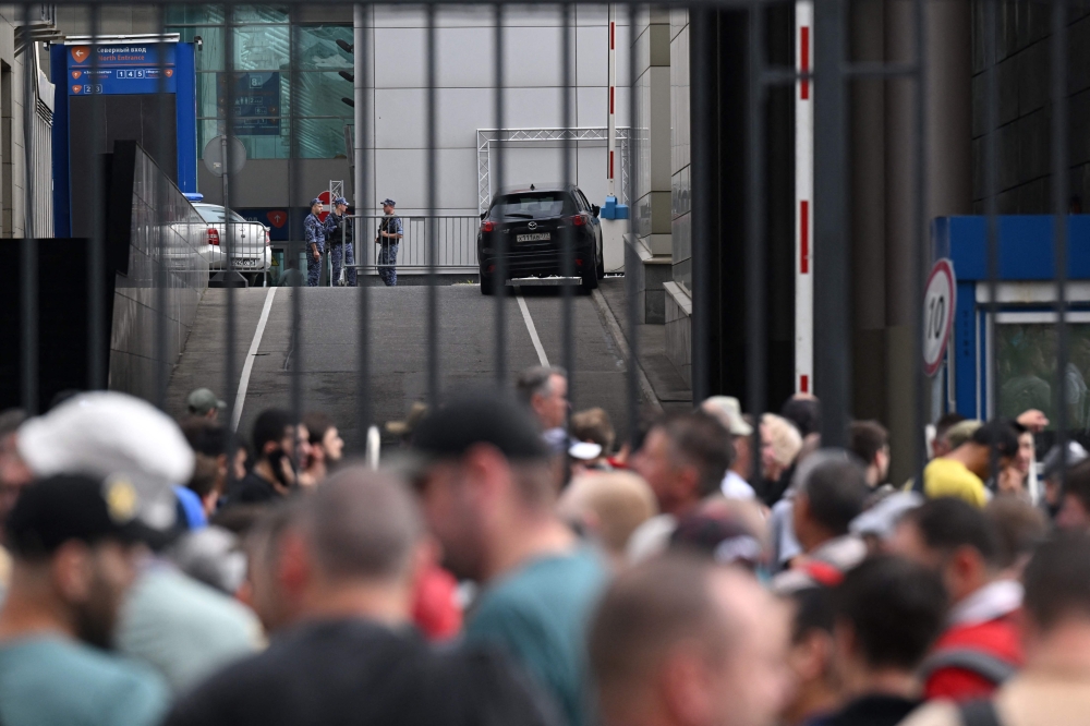 (Files) Police officers (background) secure an area as people and office workers stand in line to enter a building of Expocentre following a drone attack in Moscow on August 18, 2023. (Photo by Natalia Kolesnikova / AFP)