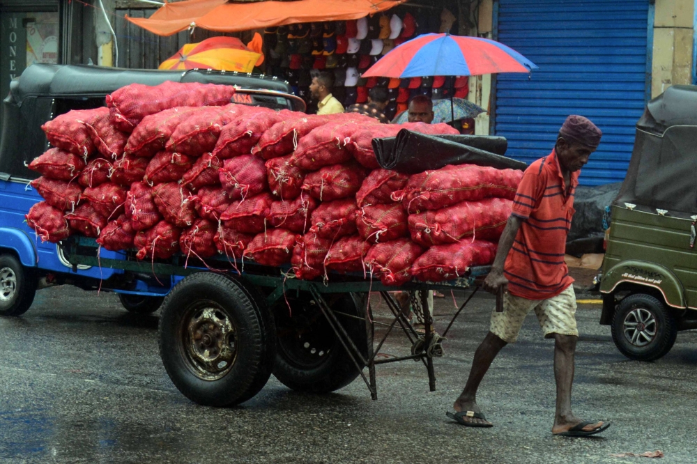 A labourer pulls a cart carrying sacks of onions at a market in Colombo on September 1, 2023. Photo by AFP