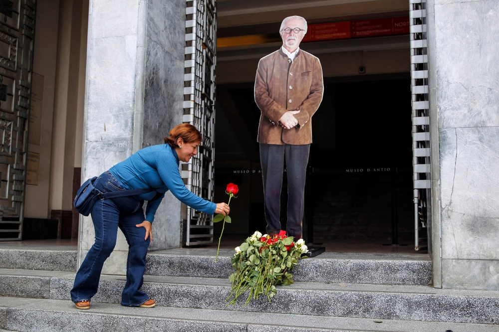 A woman lays a red rose at the feet of an image of Colombian artist Fernando Botero, at the entrance of the Antioquia Museum in Medellin, Colombia, on September 15, 2023. (Photo by Fredy Builes/ AFP)