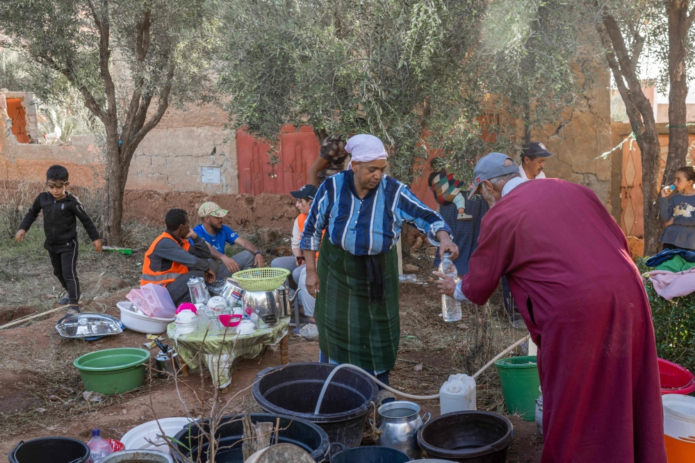 Displaced people work in a kitchen area at a makeshift encampment by the side of the road between Marrakech and Taroudant in the Atlas mountain range in the aftermath of a powerful earthquake on September 16, 2023. (Photo by Bulent Kilic / AFP)
