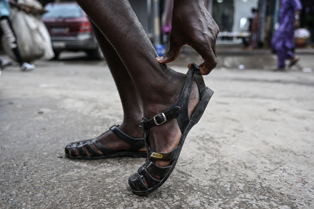 A man wears his Leke shoes in Treichville, Abidjan, on September 14, 2023. (Photo by Sia KAMBOU / AFP)
