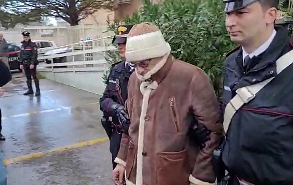 (FILES) This handout video grab taken and released by the Italian Carabinieri Press Office on January 16, 2023 shows the transfer of Italy's top wanted mafia boss, Matteo Messina Denaro (C) from the Carabinieri police station of San Lorenzo in Palermo on January 16, 2023 (Photo by Handout / ITALIAN CARABINIERI PRESS OFFICE / AFP)
