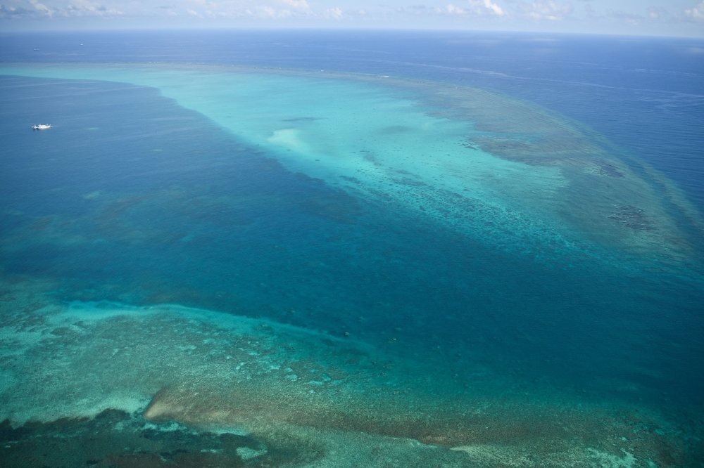 This photo taken on September 28, 2023 shows an aerial view of the mouth of the Chinese-controlled Scarborough Shoal, seen without any barriers obstructing the passageway, as Chinese coast guard ships (top L) are seen anchored inside the lagoon of the Chinese-controlled Scarborough Shoal during a maritime surveillance flight by the Philippine Bureau of Fisheries and Aquatic Resources (BFAR) over disputed waters of the South China Sea. Photo by Ted ALJIBE / AFP