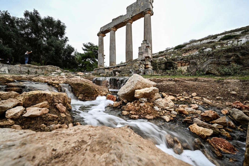 Water flows through the ruins at the site of the ancient Greco-Roman city of Cyrene (Shahhat) in eastern Libya, about 60(37 miles) west of Derna, on September 21,2023, in the aftermath of a devastating flood. (Photo by Ozan Kose / AFP)