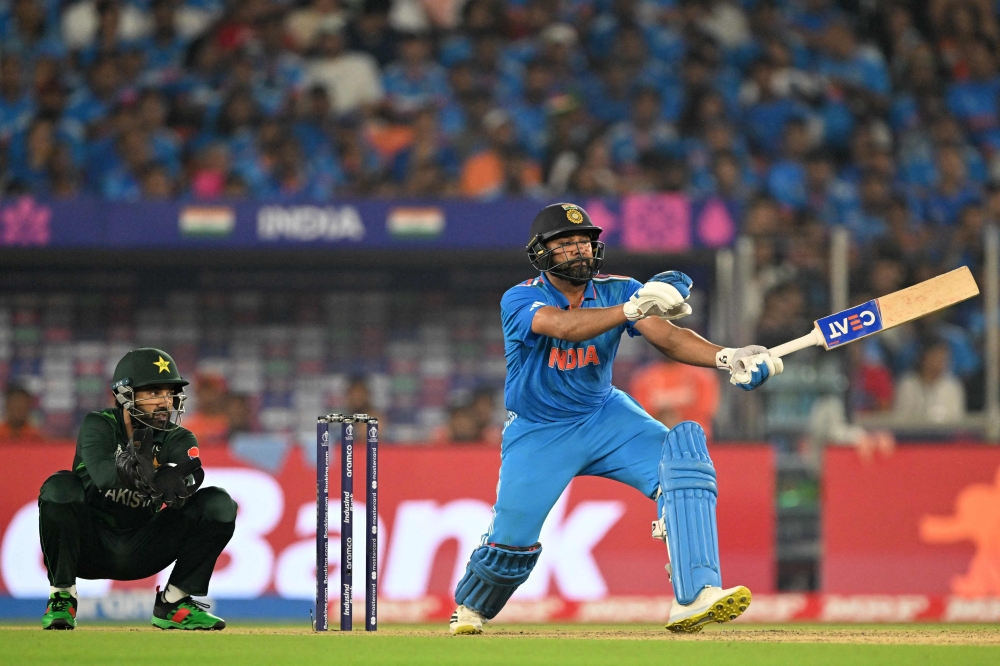 India's captain Rohit Sharma (R) plays a shot as Pakistan's wicketkeeper Mohammad Rizwan watches during the 2023 ICC Men's Cricket World Cup one-day international (ODI) match between India and Pakistan at the Narendra Modi Stadium in Ahmedabad on October 14, 2023. (Photo by Sajjad HUSSAIN / AFP)