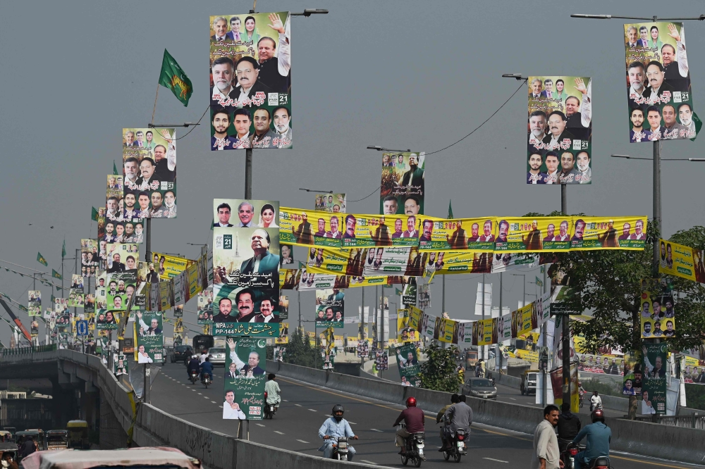 Commuters drive along a road past banners with the image of Pakistan's former Prime Minister Nawaz Sharif and Pakistan Muslim League (Nawaz) party leaders in Lahore on October 21, 2023. (Photo by Aamir Qureshi / AFP)