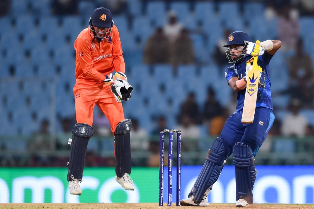 Sri Lanka's Sadeera Samarawickrama (R) plays a shot as Netherlands' captain Scott Edwards watches during the 2023 ICC Men's Cricket World Cup one-day international (ODI) match between Netherlands and Sri Lanka at the Ekana Cricket Stadium in Lucknow on October 21, 2023. (Photo by Noah SEELAM / AFP)