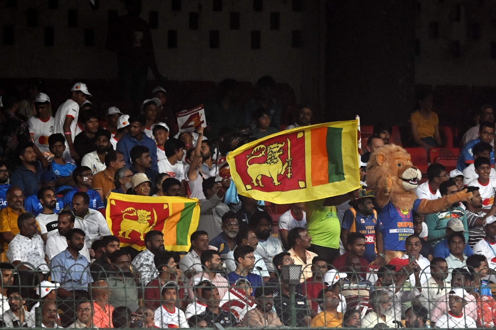 Fans hold Sri Lanka's national flags during the 2023 ICC Men's Cricket World Cup one-day international (ODI) match between England and Sri Lanka at the M. Chinnaswamy Stadium in Bengaluru on October 26, 2023. (Photo by DIBYANGSHU SARKAR / AFP)