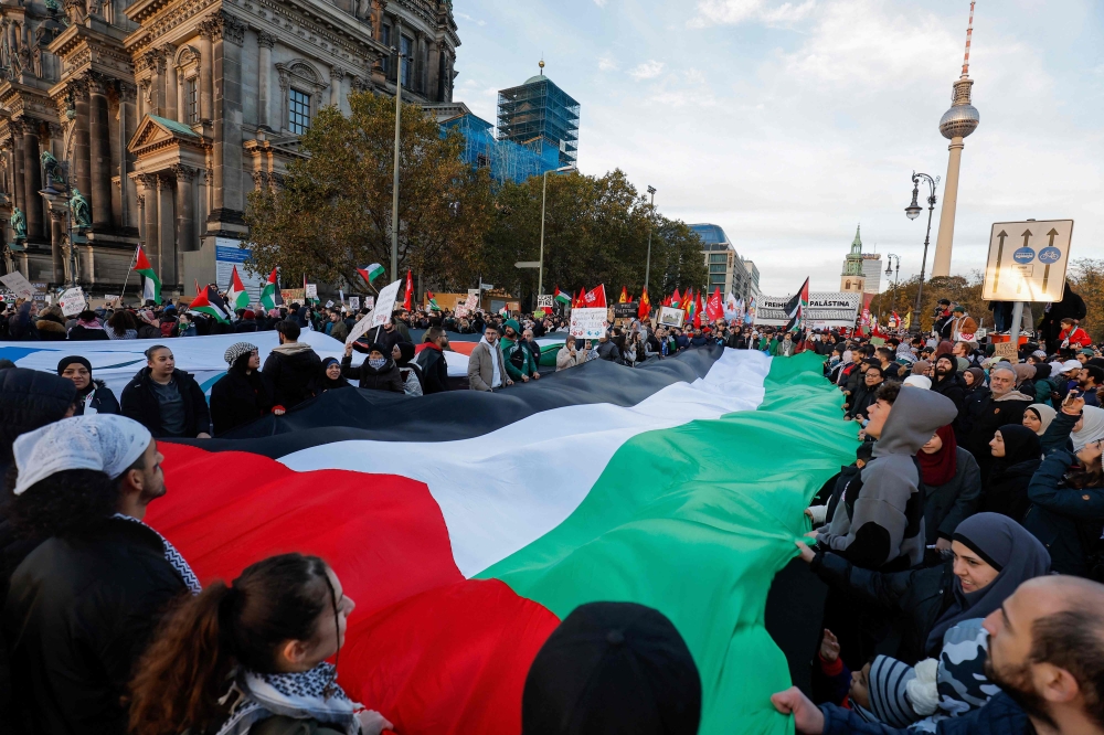 Demonstrators carry a giant Palestinian flag during a protest in support of Palestinians under the slogan 'Free Palestine' with the TV Tower in the background in Berlin, Germany on November 4, 2023. (Photo by Odd ANDERSEN / AFP)
