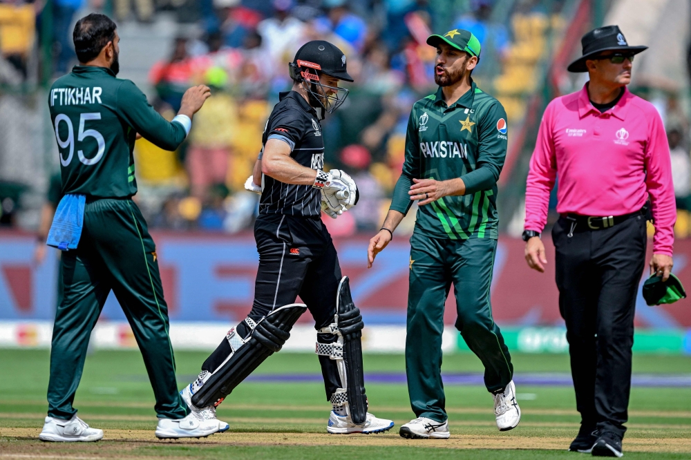 Pakistan's Iftikhar Ahmed (L) celebrates with teammate after taking the wicket of New Zealand's captain Kane Williamson (2L) during the 2023 ICC Men's Cricket World Cup one-day international (ODI) match between New Zealand and Pakistan at the M. Chinnaswamy Stadium in Bengaluru on November 4, 2023. (Photo by Sajjad HUSSAIN / AFP)
