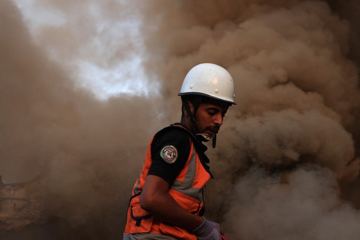 A Palestinian rescuer stands in the dust and smoke rising following a strike by the Israeli military on Khan Yunis in the southern Gaza Strip on November 4, 2023. Photo by MAHMUD HAMS / AFP
