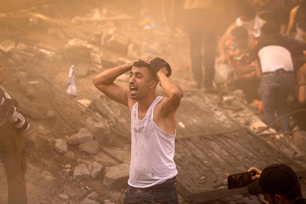 A Palestinian man reacts as others check the rubble of a building in Khan Yunis on November 6, 2023. Photo by MAHMUD HAMS / AFP