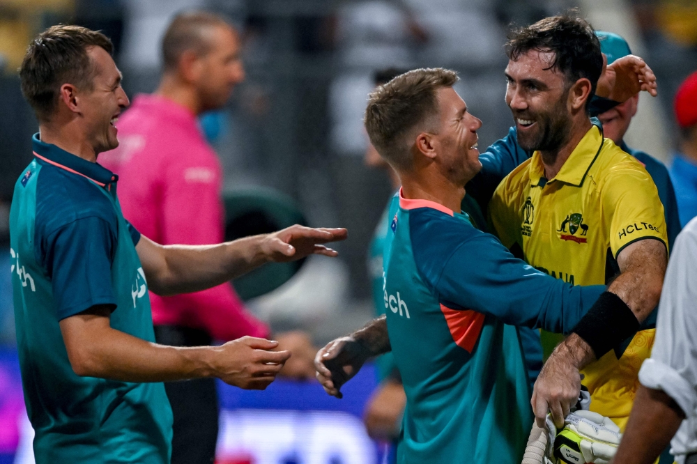Australia's Glenn Maxwell (R) celebrates with teammates after winning the 2023 ICC Men's Cricket World Cup one-day international (ODI) match between Australia and Afghanistan at the Wankhede Stadium in Mumbai on November 7, 2023. (Photo by INDRANIL MUKHERJEE / AFP)