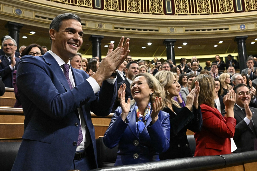 Spain's acting Prime Minister Pedro Sanchez (L) celebrates after winning a parliamentary vote to elect Spain's next premier, at the Congress of Deputies in Madrid on November 16, 2023. (Photo by Javier Soriano / AFP)