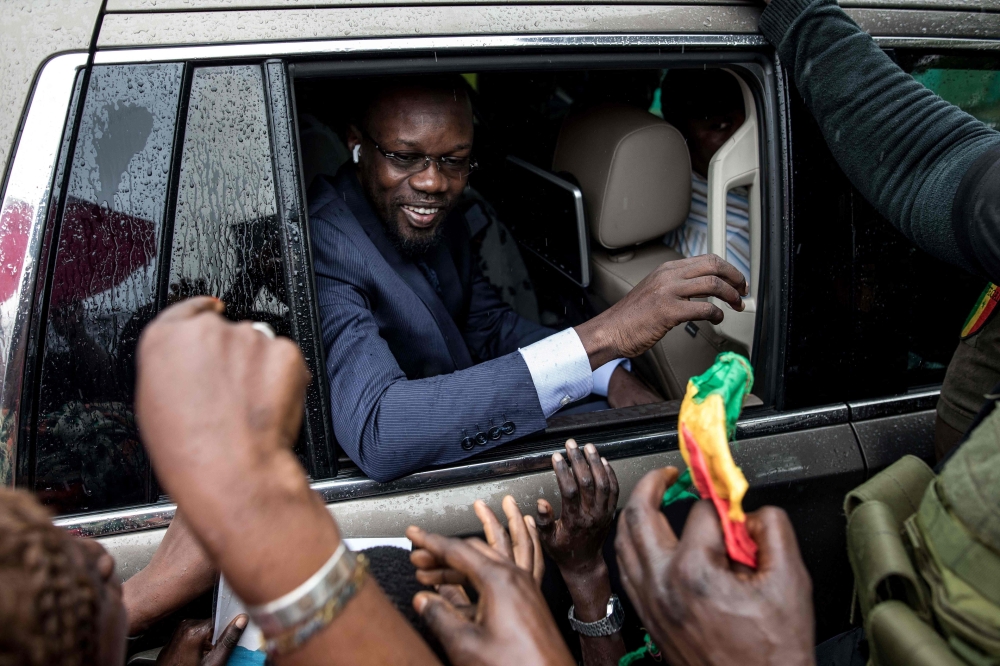 (FILES) Ousmane Sonko(C), President of the opposition party Senegalese Patriots for Work, Ethics and Brotherhood (PASTEF), waves good bye to his supporters at the HLM basic school in Ziguinchor on July 3, 2022. (Photo by MUHAMADOU BITTAYE / AFP)
