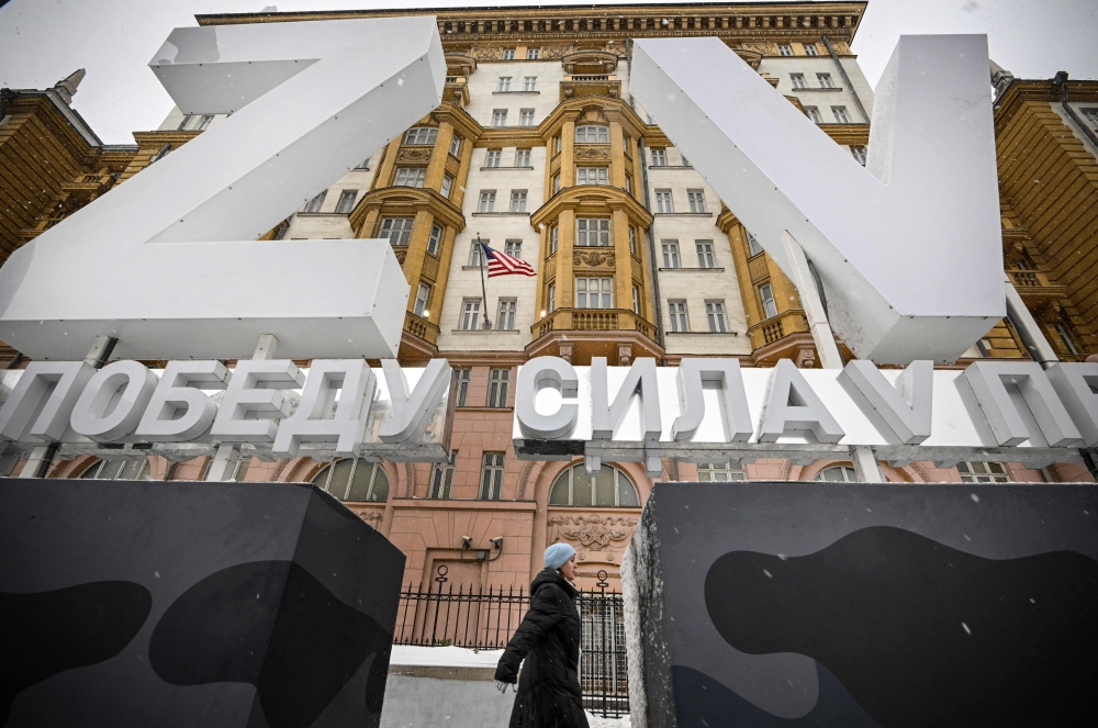A woman walks past huge Z and V letters - tactical insignias of Russian troops in Ukraine, placed in front of the US Embassy in central Moscow on November 30, 2023. (Photo by Alexander Nemenov / AFP)