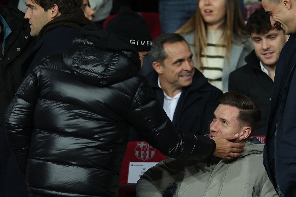 Former player of Barcelona Jordi Alba (L) caresses Barcelona's German goalkeeper #01 Marc-Andre ter Stegen's face during the Spanish league football match between FC Barcelona and Club Atletico de Madrid at the Estadi Olimpic Lluis Companys in Barcelona on December 3, 2023. (Photo by LLUIS GENE / AFP)
