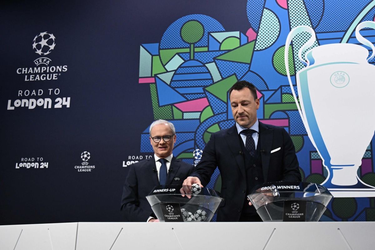 British former football player, John Terry (right) handles a draw ball alongside UEFA Deputy General Secretary, Giorgio Marchetti during the 2023-2024 UEFA Champions League Round of 16 draw in Nyon. AFP