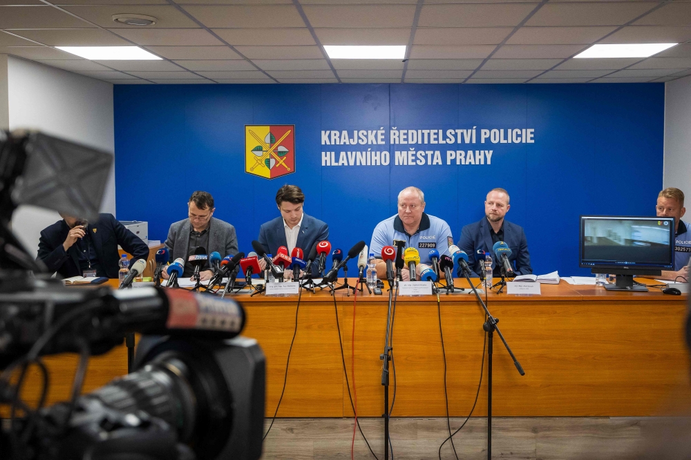 Prague's Police chief Petr Matejcek (C-R, in blue shirt) addresses a press conference on December 22, 2023 in Prague to inform about a deadly mass shooting at a university the day before. Photo by Radek Mica / AFP
