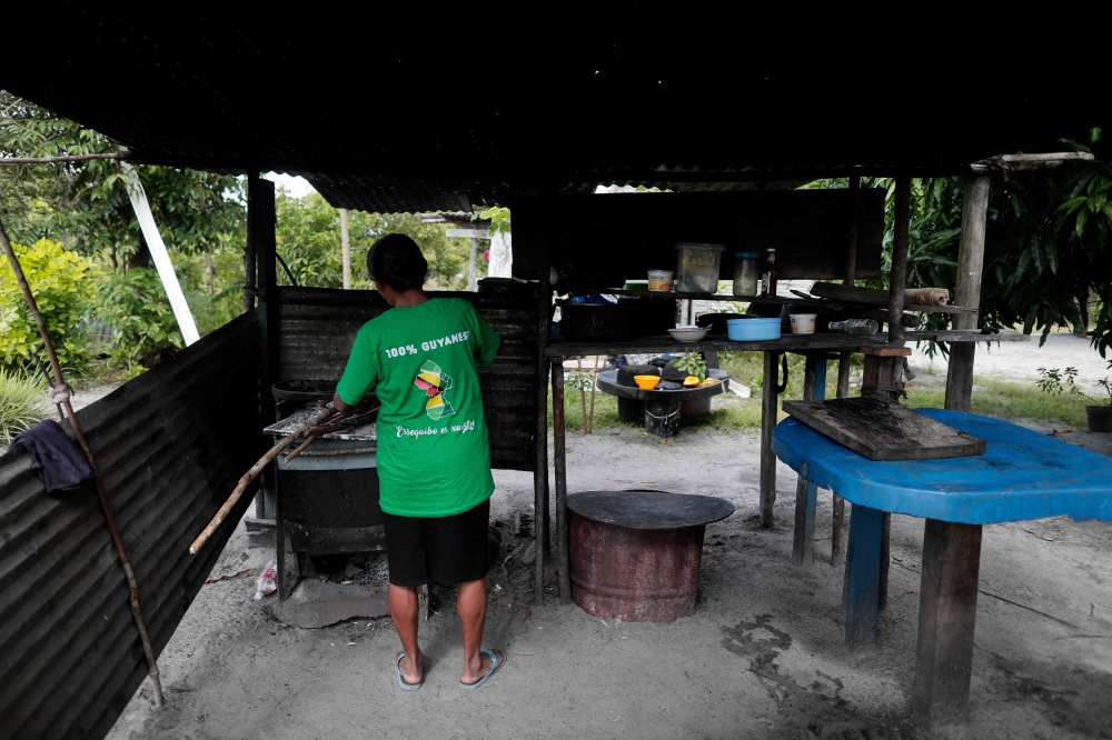 A woman cooks at the Arau village in Guyana on December 10, 2023. (Photo by Roberto CISNEROS / AFP)


