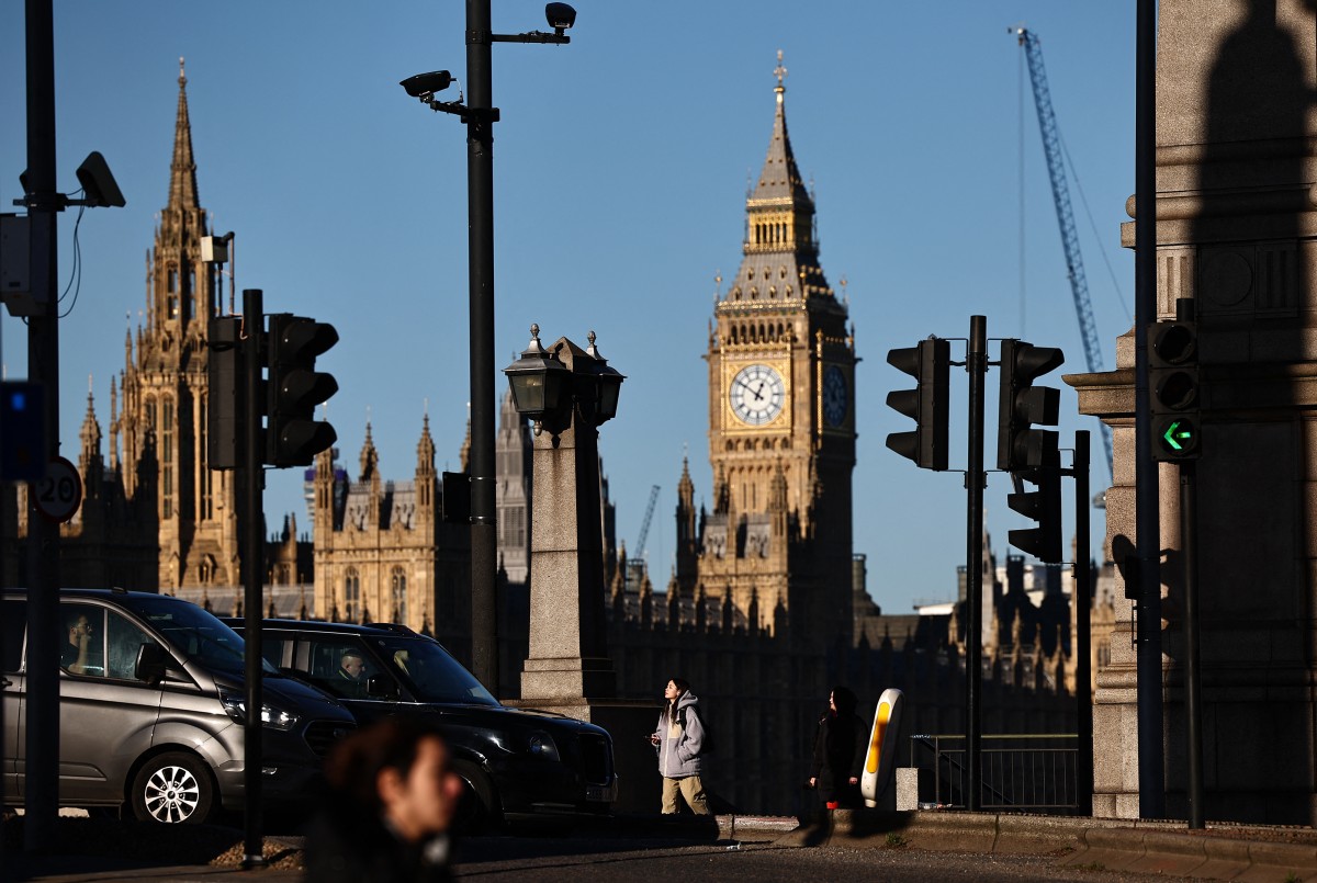 A pedestrian passes CCTV cameras a road junction on the south bank of the River Thames, as The Elizabeth Tower, commonly known by the name of the clock's bell, 
